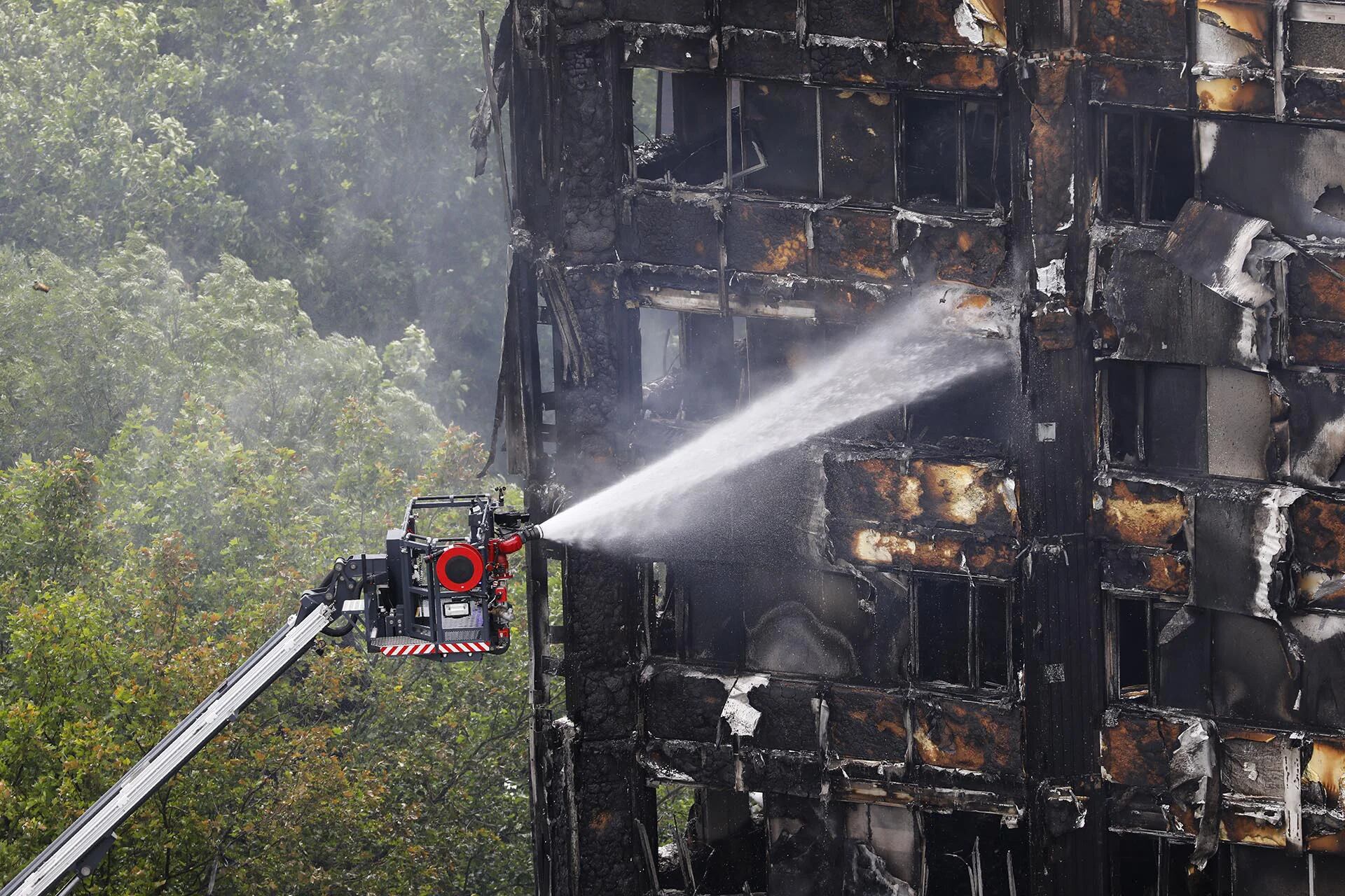 Una manguera automatizada rocía el agua sobre la incendiada torre Grenfell en Londres