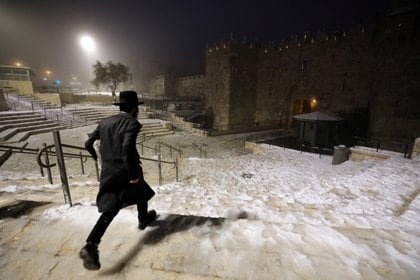 Un judío ultraortodoxo entra en la ciudad vieja de Jerusalén por la puerta de Damasco cubierta por nieve (REUTERS / Ammar Awad)