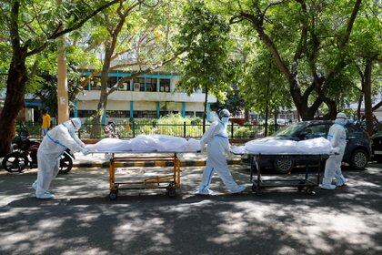 Trabajadores sanitarios con equipos de protección personal (EPP) transportan cadáveres en el exterior del hospital Guru Teg Bahadur, en Nueva Delhi, India, el 24 de abril de 2021 (REUTERS/Adnan Abidi)
