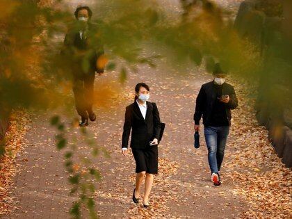 Transeúntes con mascarillas caminan bajo hojas de colores otoñales, en medio del brote de la enfermedad del coronavirus (COVID-19), en Tokio, Japón. 19 de noviembre de 2020. REUTERS/Issei Kato