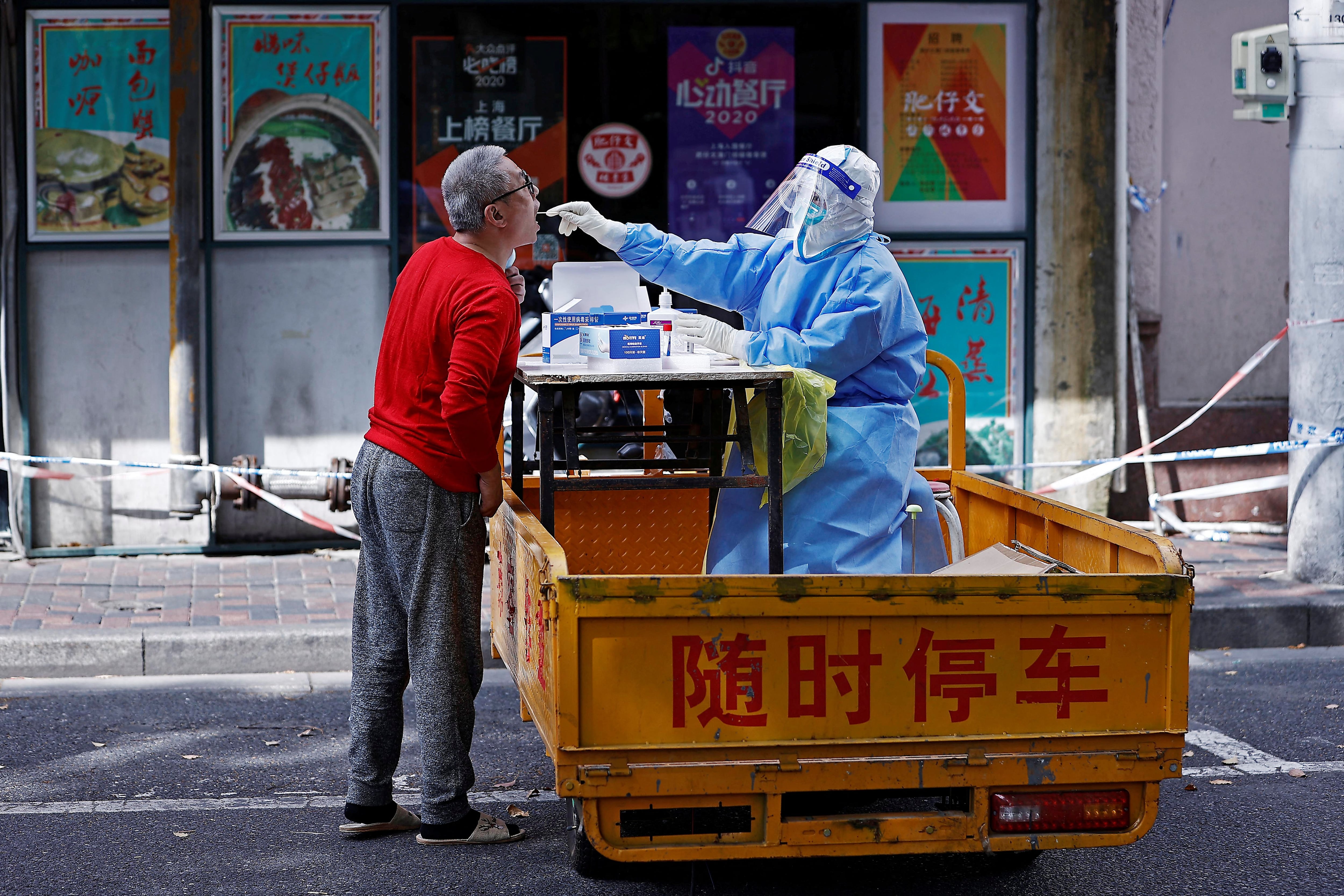 Un trabajador sanitario con traje de protección recoge un hisopo de un residente para realizar pruebas de ácido nucleico, en medio del brote de la enfermedad por coronavirus y de política de Covid Cero en Shanghái, una ciudad paralizada por las restricciones (Reuters)