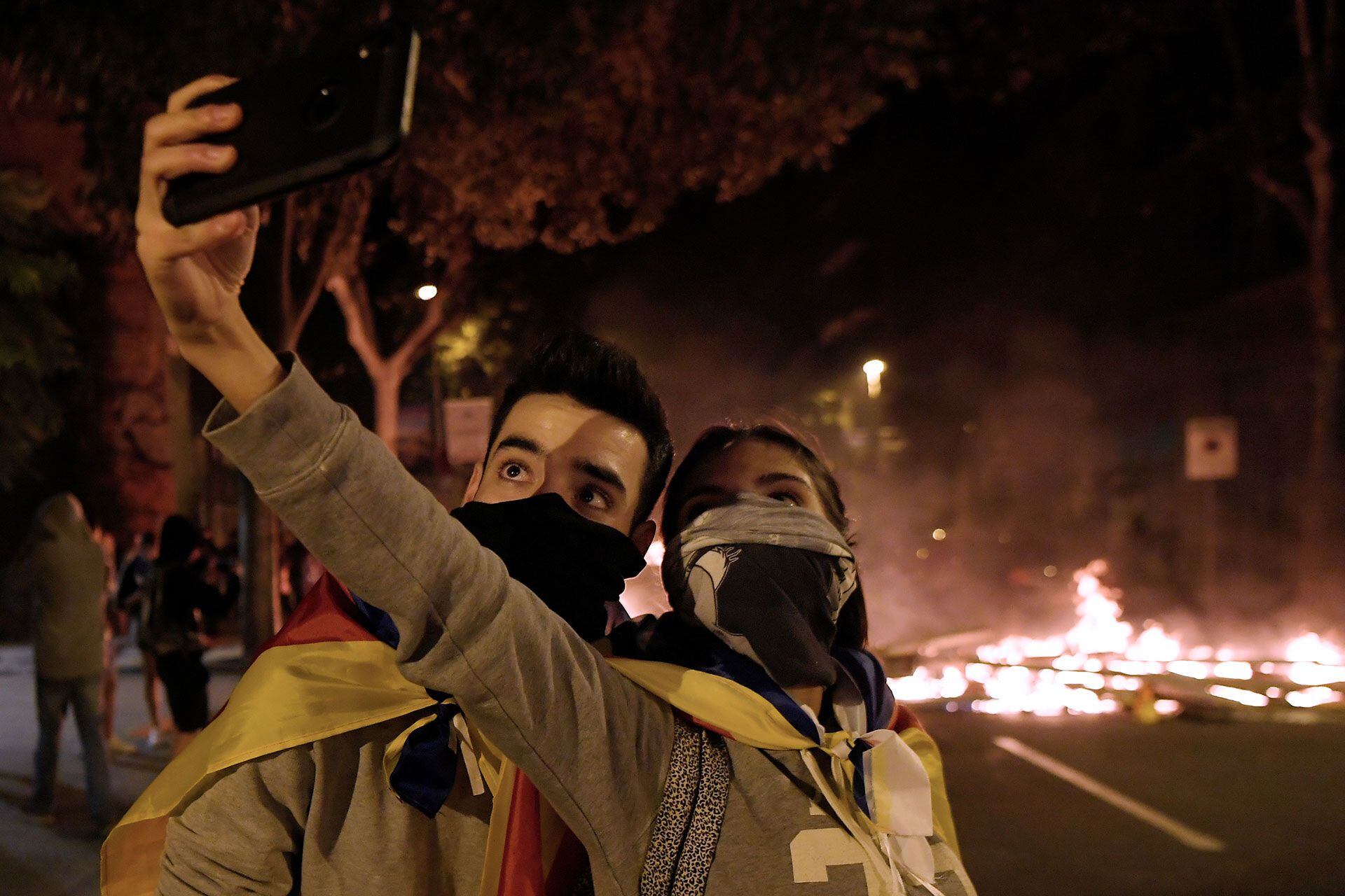 Dos jóvenes se toman una selfie frente a una de las barricadas montadas por las protestas en Barcelona (Photo by LLUIS GENE / AFP)