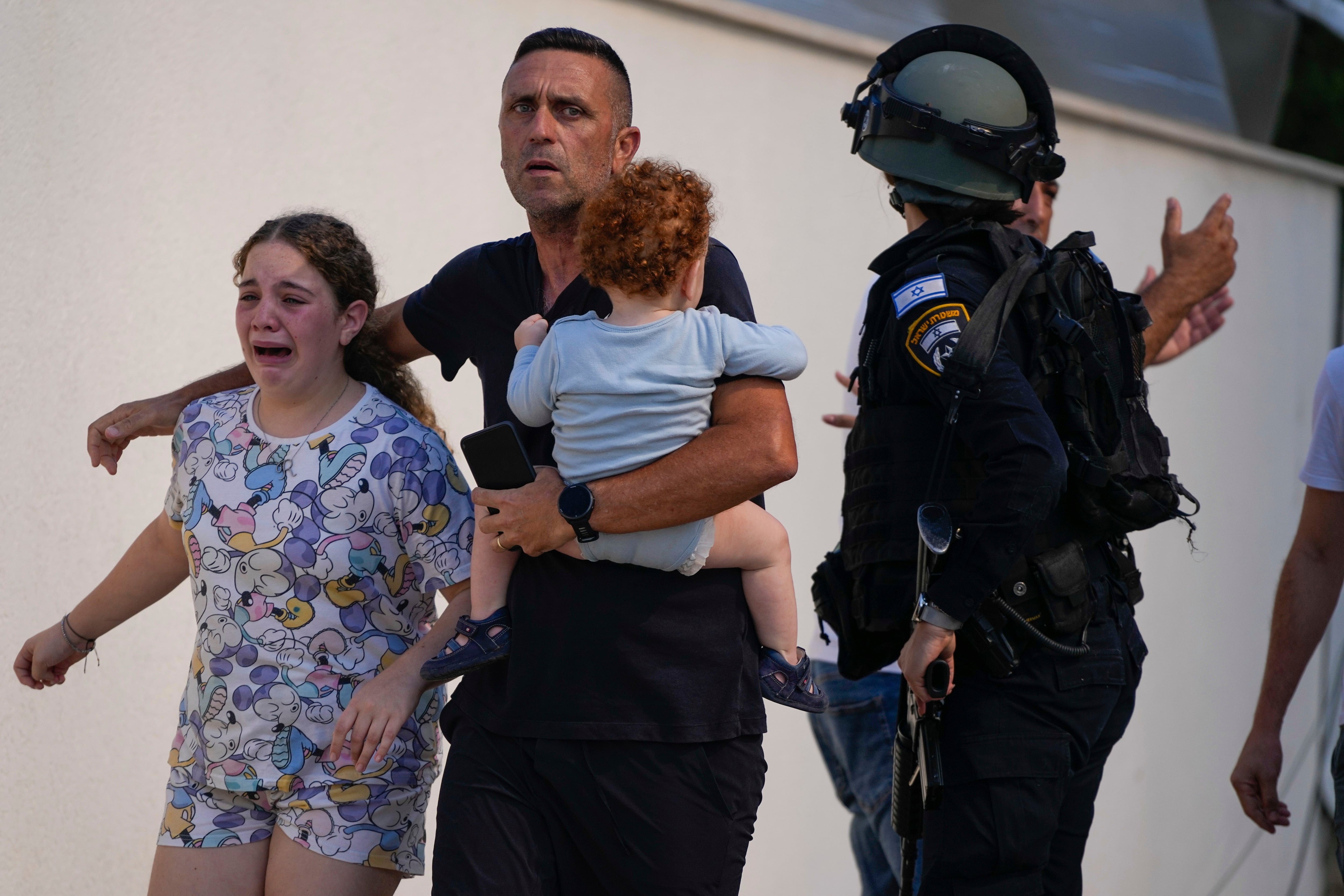 Israeli police officers evacuate a family from a place hit by a rocket fired from the Gaza Strip, in Ashkelon, (AP Photo/Tsafrir Abayov)