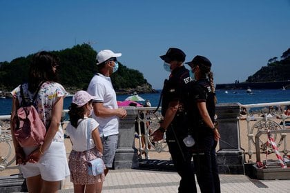 Una familia con mascarillas habla con la policía en la playa de Ondarreta en San Sebastián, España, el 30 de mayo, 2020. REUTERS/Vincent West