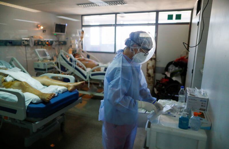 Un trabajador de la salud monitoréa a pacientes de COVID-19 en una unidad de cuidados intensivos en un hospital en las afueras de Buenos Aires, Argentina April 16, 2021. Foto tomada a través de un vidrio. REUTERS/Agustin Marcarian