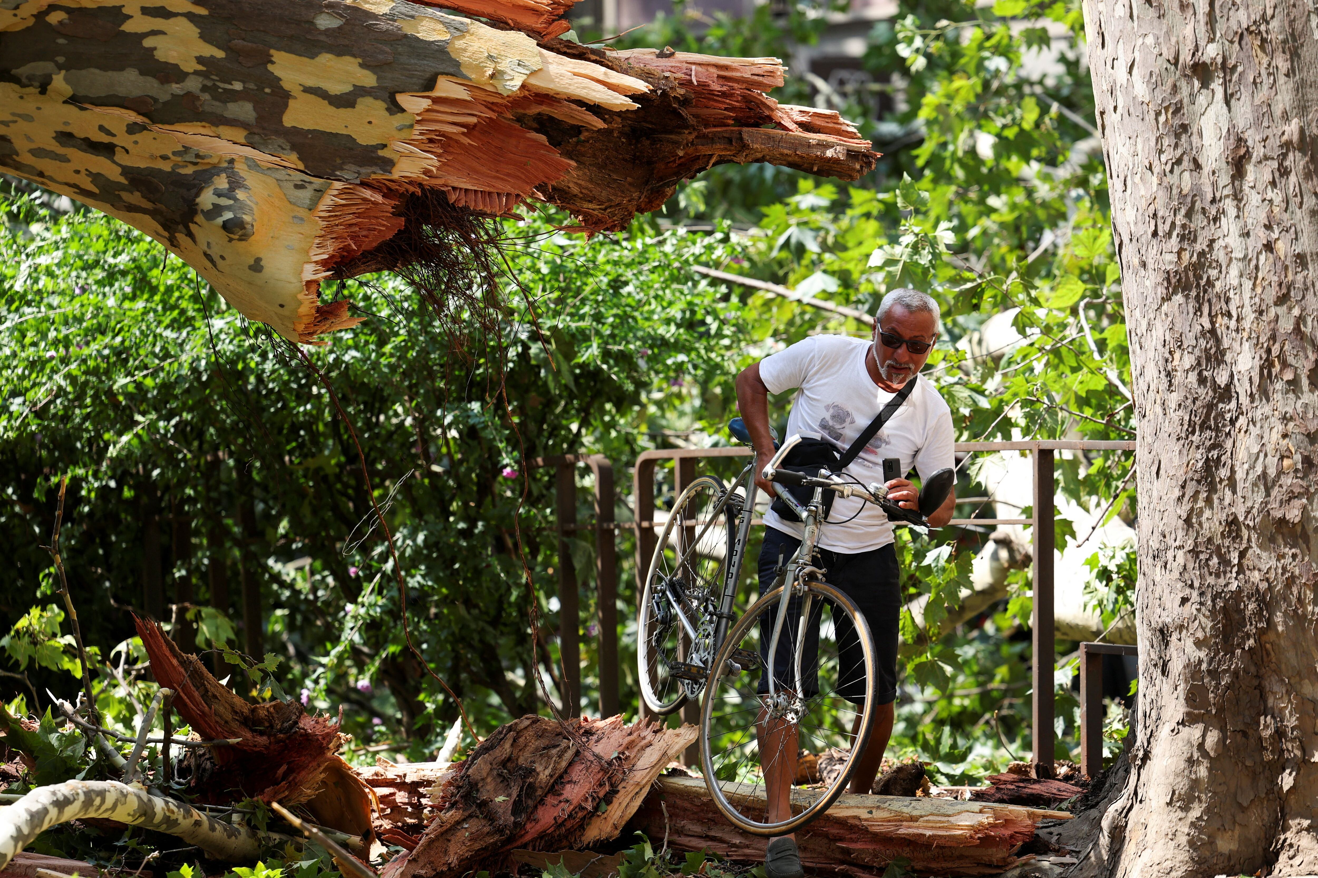 Un hombre con su bici entre los árboles caídos en Milán (REUTERS/Claudia Greco)