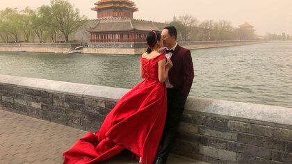 A wedding couple poses for photos near the Forbidden City amid a sandstorm in Beijing on Sunday, March 28, 2021. (AP Photo/Sam McNeill)