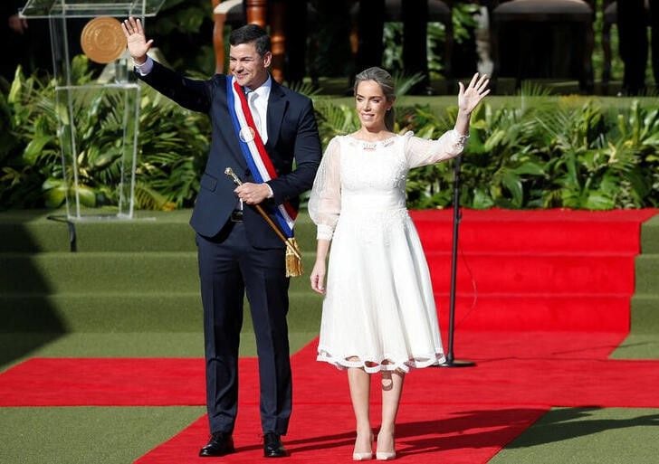 El nuevo presidente de Paraguay, Santiago Peña, usa la banda presidencial y sostiene el bastón de mando mientras saluda a la gente con la primera dama Leticia Ocampos (REUTERS/Cesar Olmedo)