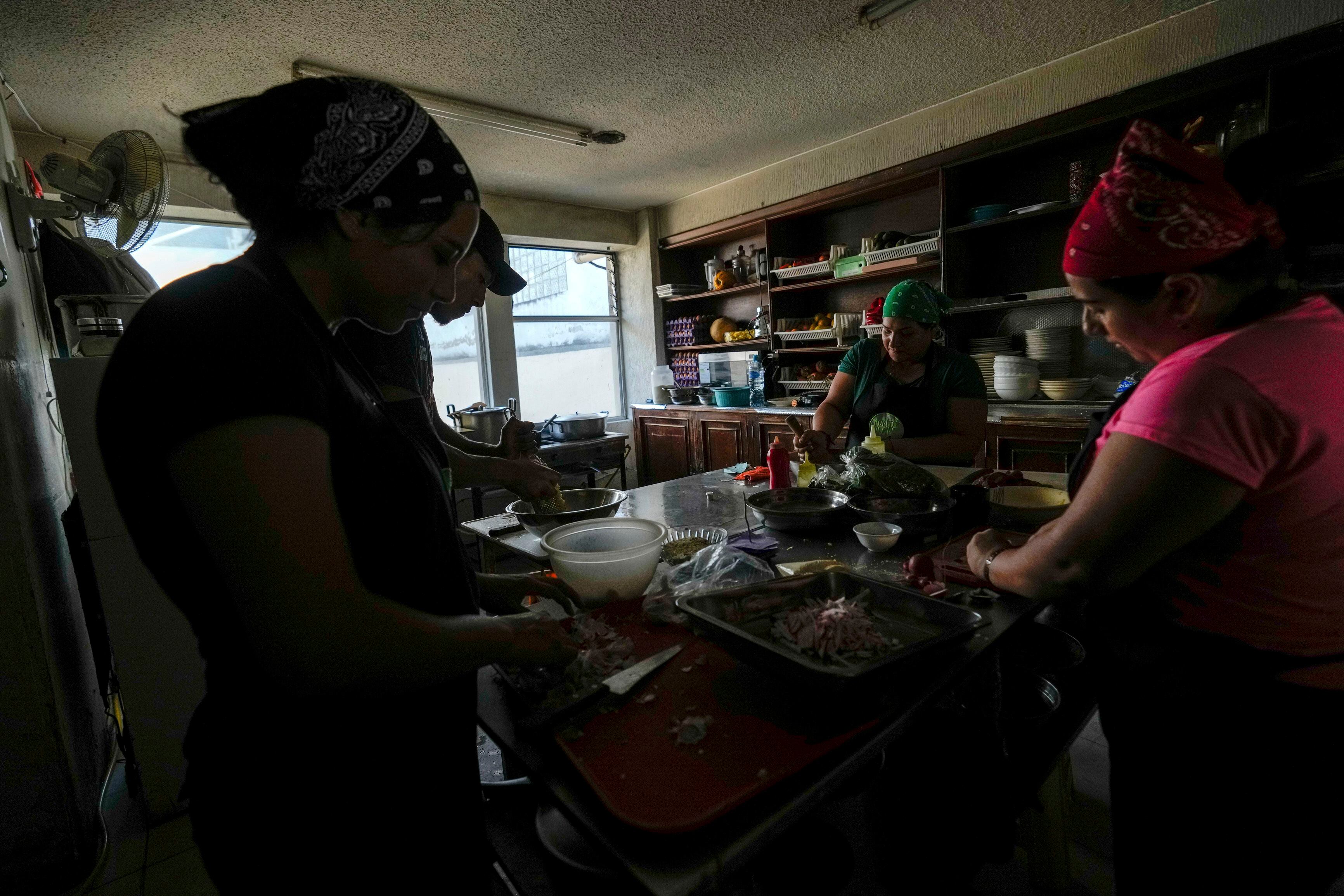 Empleados de un restaurantes intentan seguir con su trabajo utilizando utensilios de cocina manuales ante los cortes de energía dispuestos por el Ministerio de Energía, en Quito (AP Foto/Dolores Ochoa)