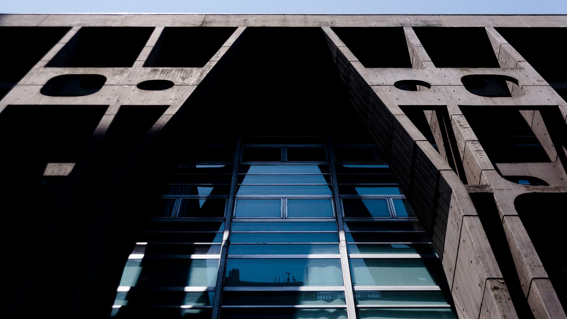 El edificio recompone las líneas municipales de las calles en las que está emplazado con una pantalla de hormigón a la vista modelado artesanalmente