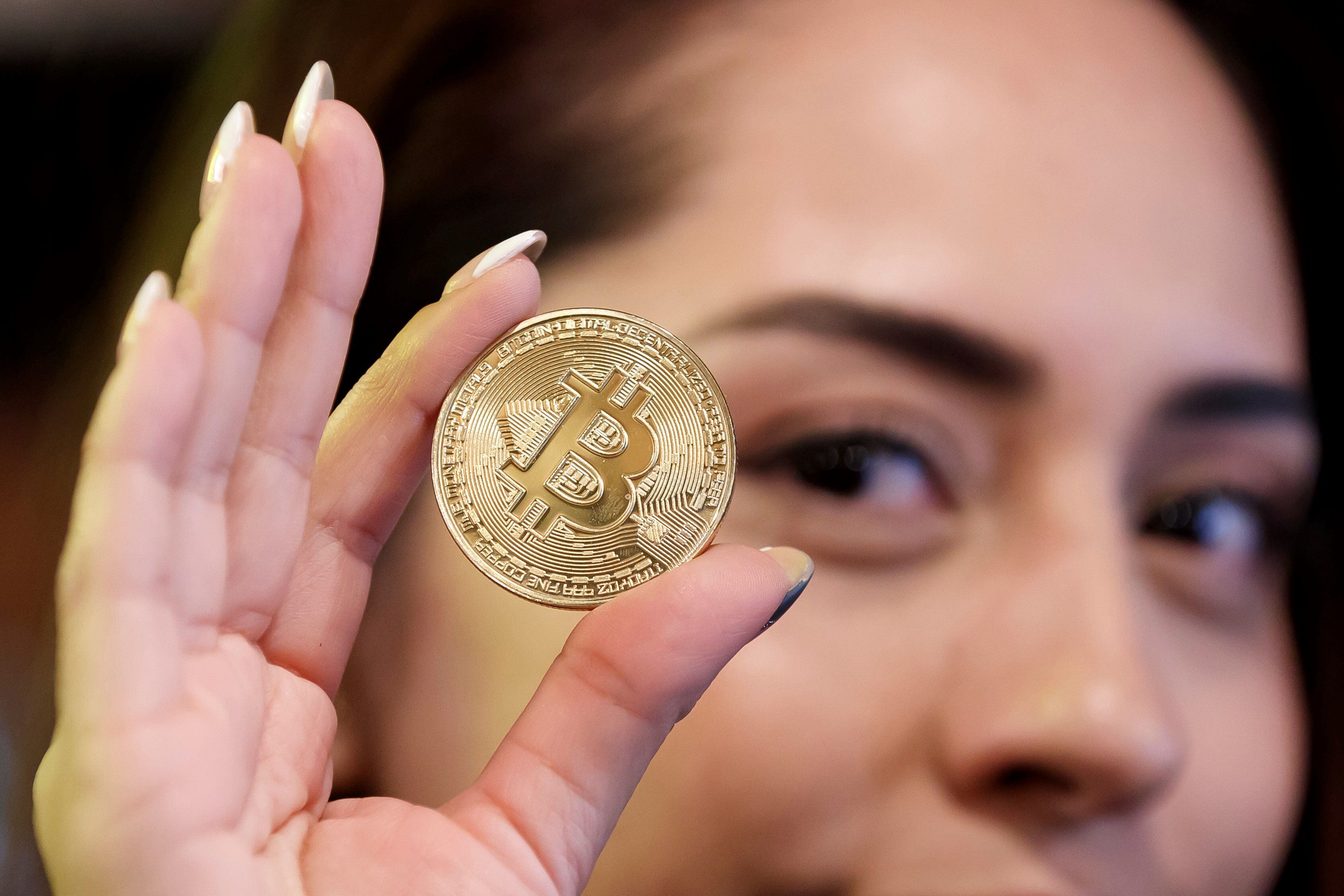 Una mujer sostiene una moneda de bitcoin en una imagen de archivo. EFE/José Méndez