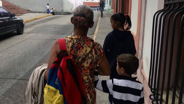 Una abuela que quedó al cuidado de cuatro nietos camina por las calles de Caracas tras recoger a dos de ellos en la escuela.