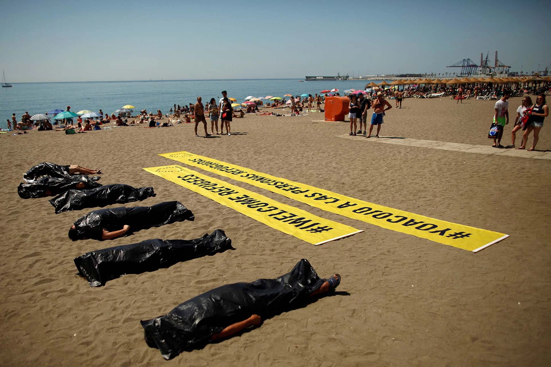 Para conmemorar el Día Mundial de los Refugiados, activistas de Amnistía Internacional participan en una actuación en Málaga que simula la muerte de inmigrantes en el Mar Mediterráneo