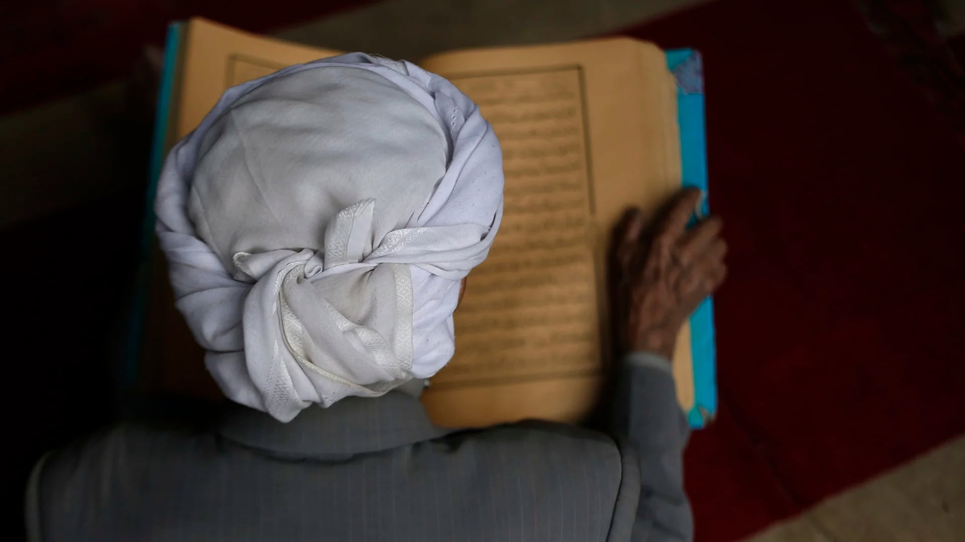 Un hombre lee versos del Corán, el libro sagrado del islam, en el primer día del mes de ayuno del Ramadán en la Gran Mezquita de la ciudad vieja de Sanaa, Yemen (AFP)