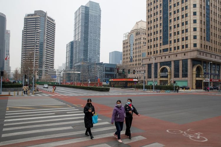 Personas usan máscaras de protección mientras cruzan una calle en el Distrito Comercial Central de Pekín, en momentos en que China se ve afectada por un brote del nuevo coronavirus, en Pekín, Febrero 24, 2020. REUTERS/Thomas Peter