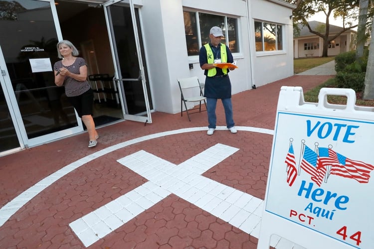 Una votante se limpia con alcohol en gel al salir de un local de votación (AP)
