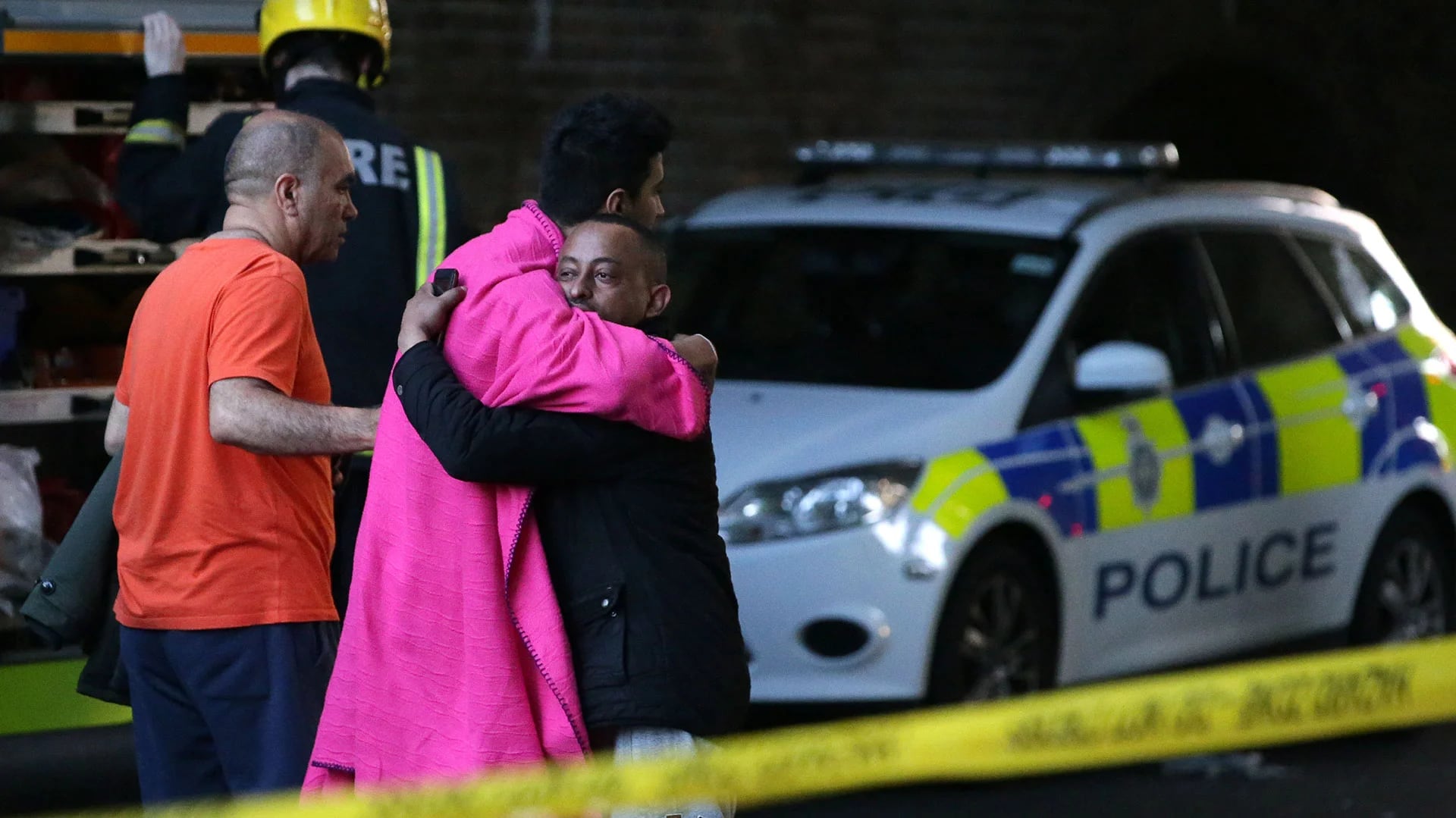 Dos hombres se abrazan al encontrarse tras el incendio de la torre que enluta a Reino Unido (AFP)