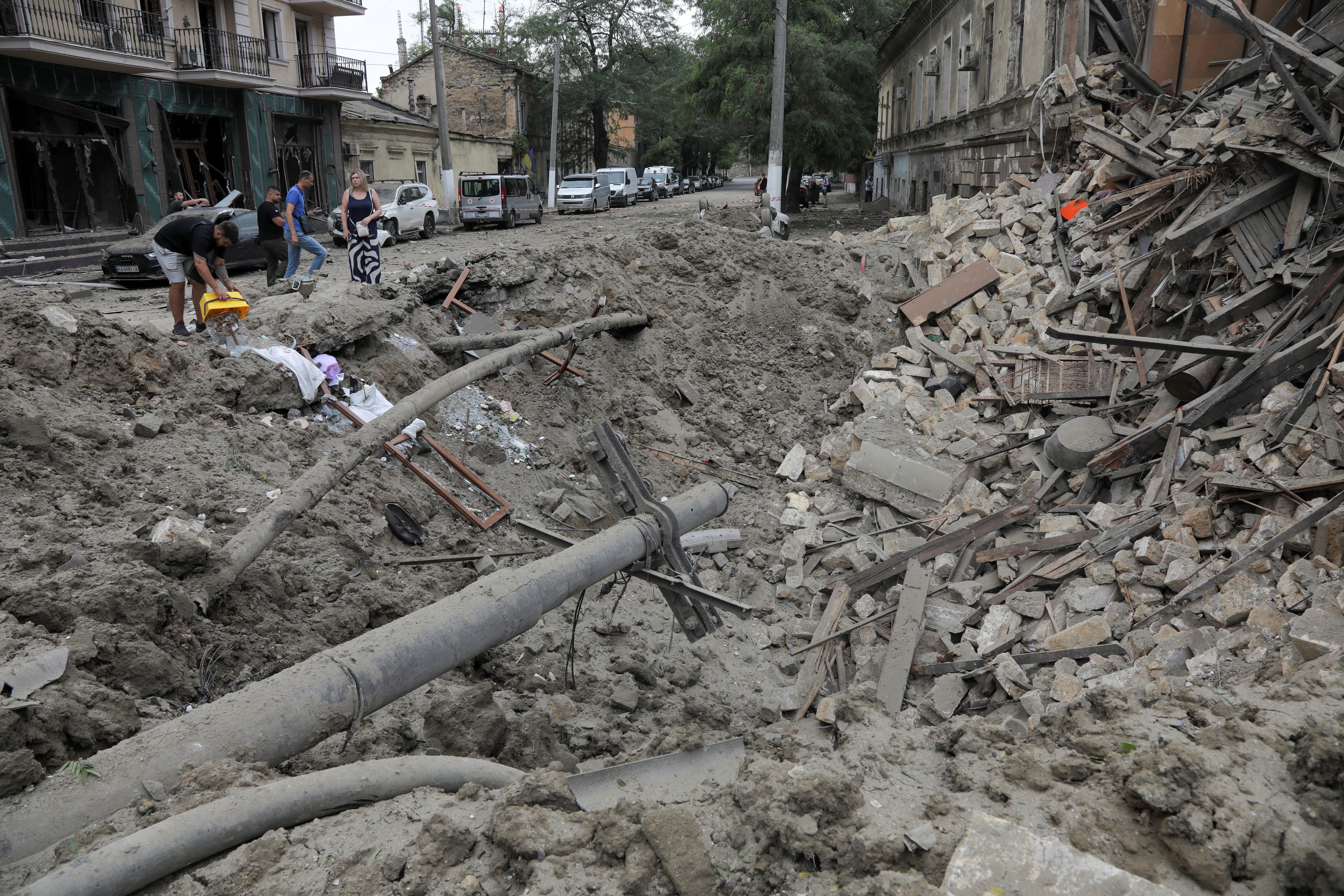 La gente se para junto a los escombros en el sitio de un edificio residencial dañado durante los ataques con misiles rusos, en medio del ataque de Rusia a Ucrania, en Odesa, Ucrania, el 23 de julio de 2023. REUTERS/Nina Liashonok