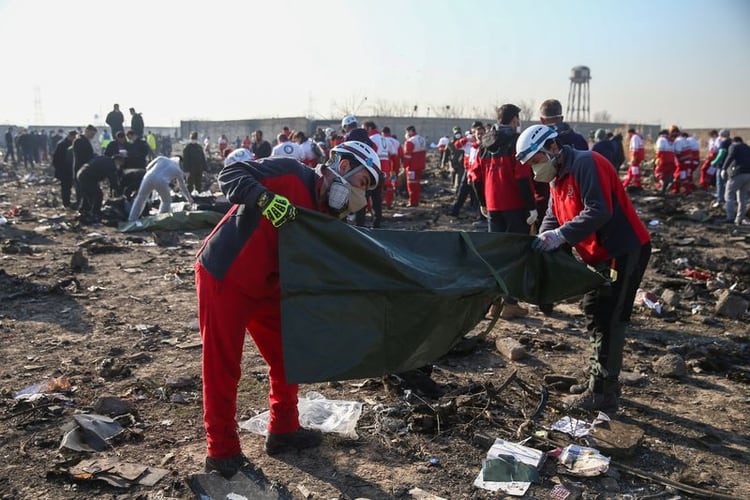 Trabajadores de la Media Luna Roja revisan bolsas de plástico en el sitio donde el avión de Ukraine International Airlines se estrelló después del despegue del aeropuerto iraní Imán Jomeini, en las afueras de Teherán (Reuters)