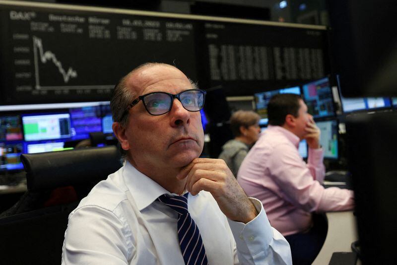 FOTO DE ARCHIVO: Un agente de bolsa mira sus pantallas frente al gráfico del índice de precios de acciones. REUTERS/Kai Pfaffenbach
