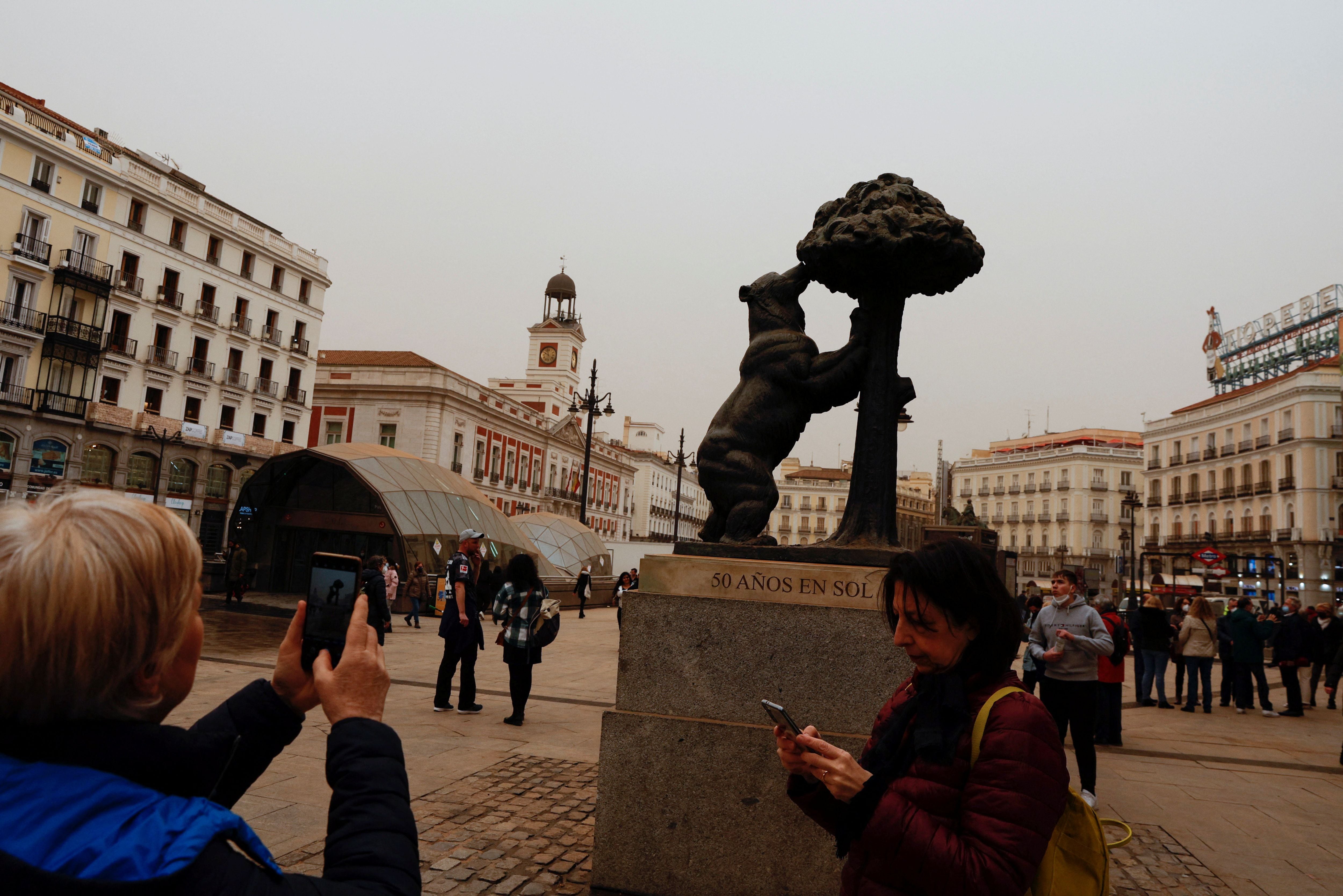 Tourists take pictures of Puerta del Sol square as storm Celia blew sand from the Sahara desert over Madrid, Spain, March 15, 2022. REUTERS/Susana Vera