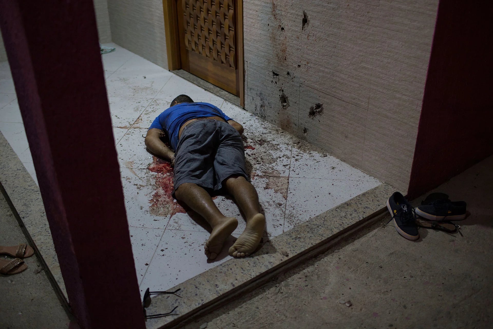 La imagen muestra el cuerpo de un hombre asesinado a tiros en el interior de su casa. Las escenas de impunidad y violencia se repiten a diario en las vecindades de Río (AP)