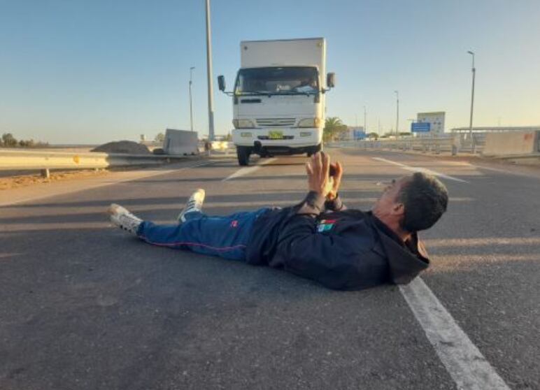 Un migrante extranjero se coloca en el suelo de la carretera en la frontera entre Perú y Chile para impedir el tránsito.