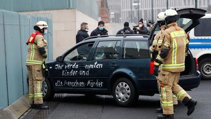 Firefighters remove the car which crashed into the gate of the main entrance of the chancellery in Berlin, the office of German Chancellor Angela Merkel in Berlin, Germany, November 25, 2020. Letters written on the car read: "You damn killers of children and old people".     REUTERS/Fabrizio Bensch