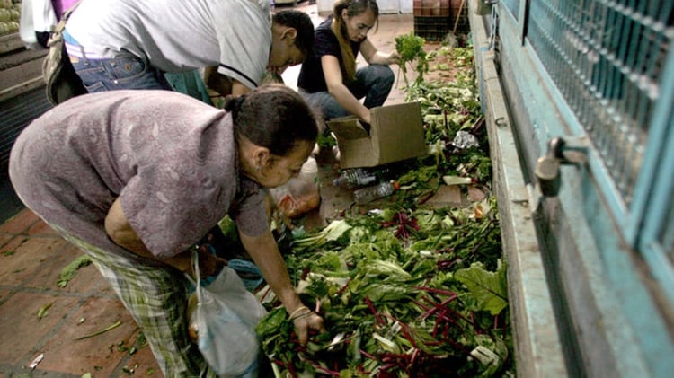 Un grupo de personas busca comida entre la basura de un mercado de Caracas. 