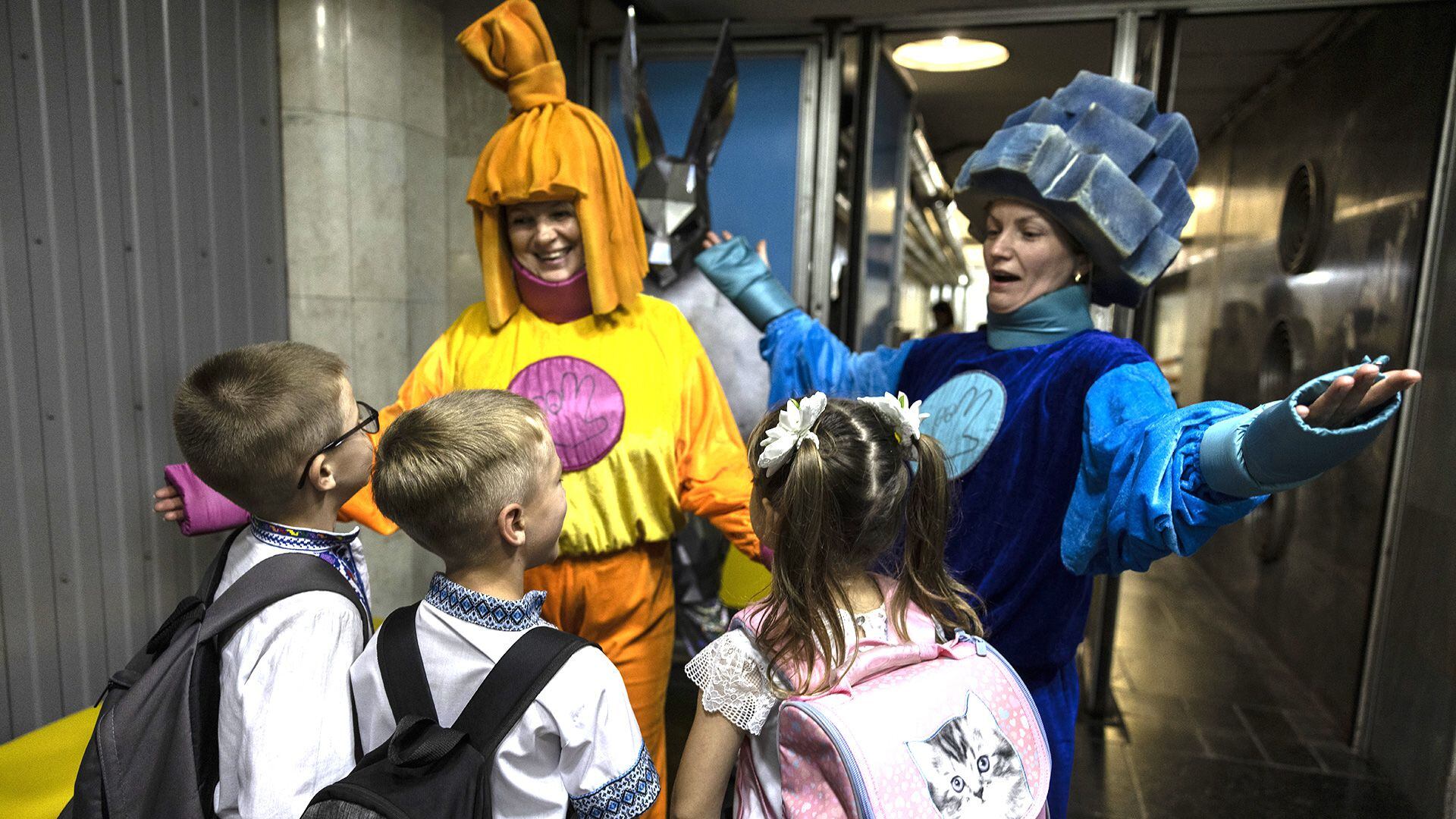 Mujeres disfrazadas dan la bienvenida a alumnos de primer curso antes de acompañar a los niños a su clase en la estación de metro subterránea de Kharkiv, Ucrania (Fotografía de Heidi Levine para The Washington Post)