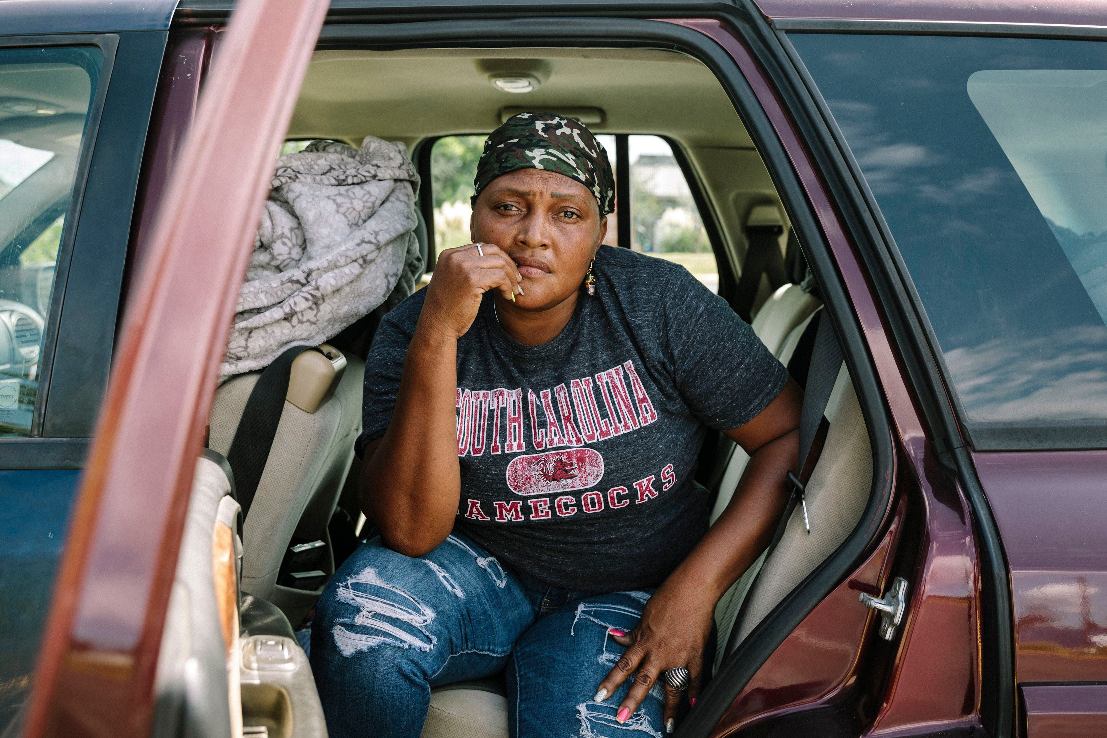 Sinia, de Honduras, se sienta en el automóvil del que ha estado viviendo durante ocho meses mientras realizaba trabajos de reparación tras el huracán (William Widmer/The New York Times)