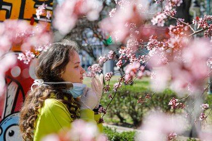 A girl removes the mask to smell the flowers on a blooming tree following the outbreak of the coronavirus disease (COVID-19) in Skopje, North Macedonia March 20, 2020. REUTERS/Ognen Teofilovski