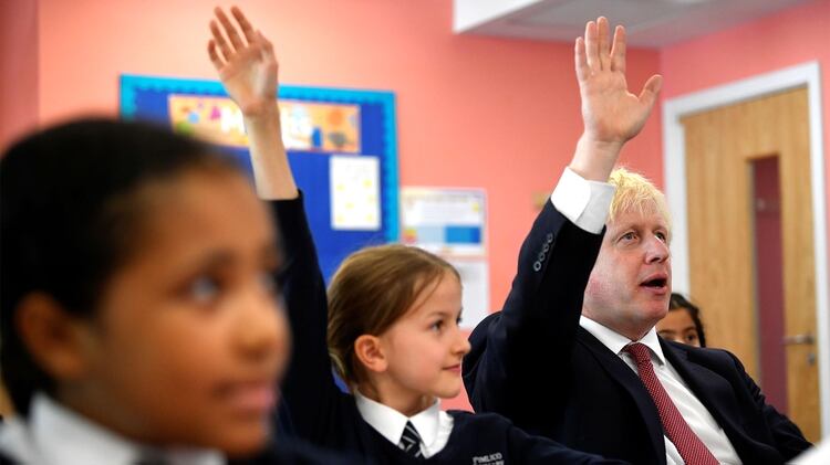 Boris Johnson levanta la mano para responder a una pregunta mientras asiste a una clase de historia de cuarto grado durante una visita a la escuela primaria Pimlico en Londres, el 10 de septiembre (REUTERS/Toby Melville/Pool)