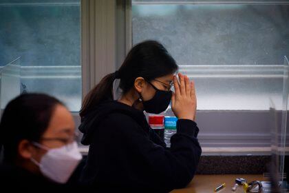 Una estudiante, con mascarilla por la pandemia del coronavirus, reza antes del inicio del examen anual de entrada a la universidad, en Seúl, Corea del Sur, el 3 de diciembre de 2020. (Kim Hong-Ji/Pool Photo via AP)