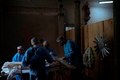 Enfermeros acomodan el cuerpo de un fallecido en una morgue improvisada en la iglesia del hospital Centenario, el 23 de marzo de 2021, en São Leopoldo, Rio Grande do Sul (EFE/ Daniel Marenco/Archivo)
