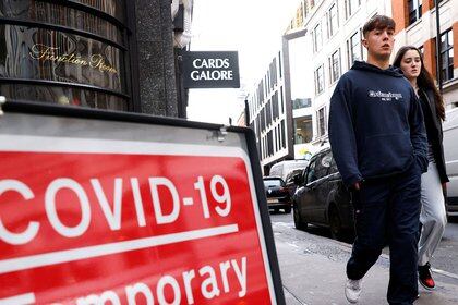 A coronavirus disease (COVID-19) sign is seen as people walk, in the Soho area, in London Britain October 15, 2020. REUTERS/John Sibley