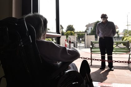 An elderly resident of a nursing home speaks to a relative who stands behind a barrier to keep a safe distance, as the spread of the coronavirus disease (COVID-19) continues in Capralba, near Cremona, Italy May 22, 2020. Picture taken May 22, 2020. REUTERS/Flavio Lo Scalzo