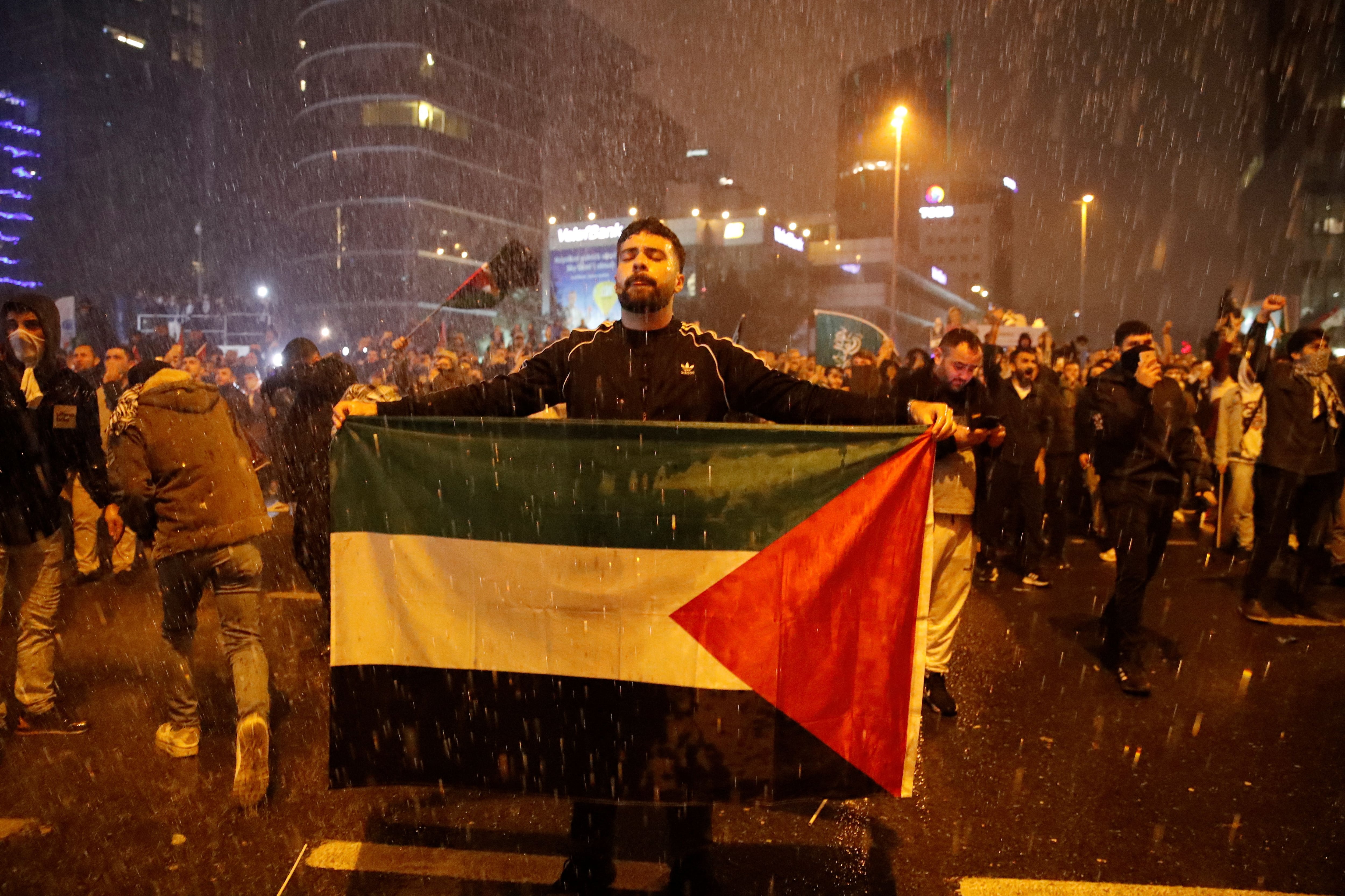 Un hombre sostiene una bandera palestina mientras la policía antidisturbios turca utiliza cañones de agua para dispersar a manifestantes propalestinos (REUTERS/Dilara Senkaya)