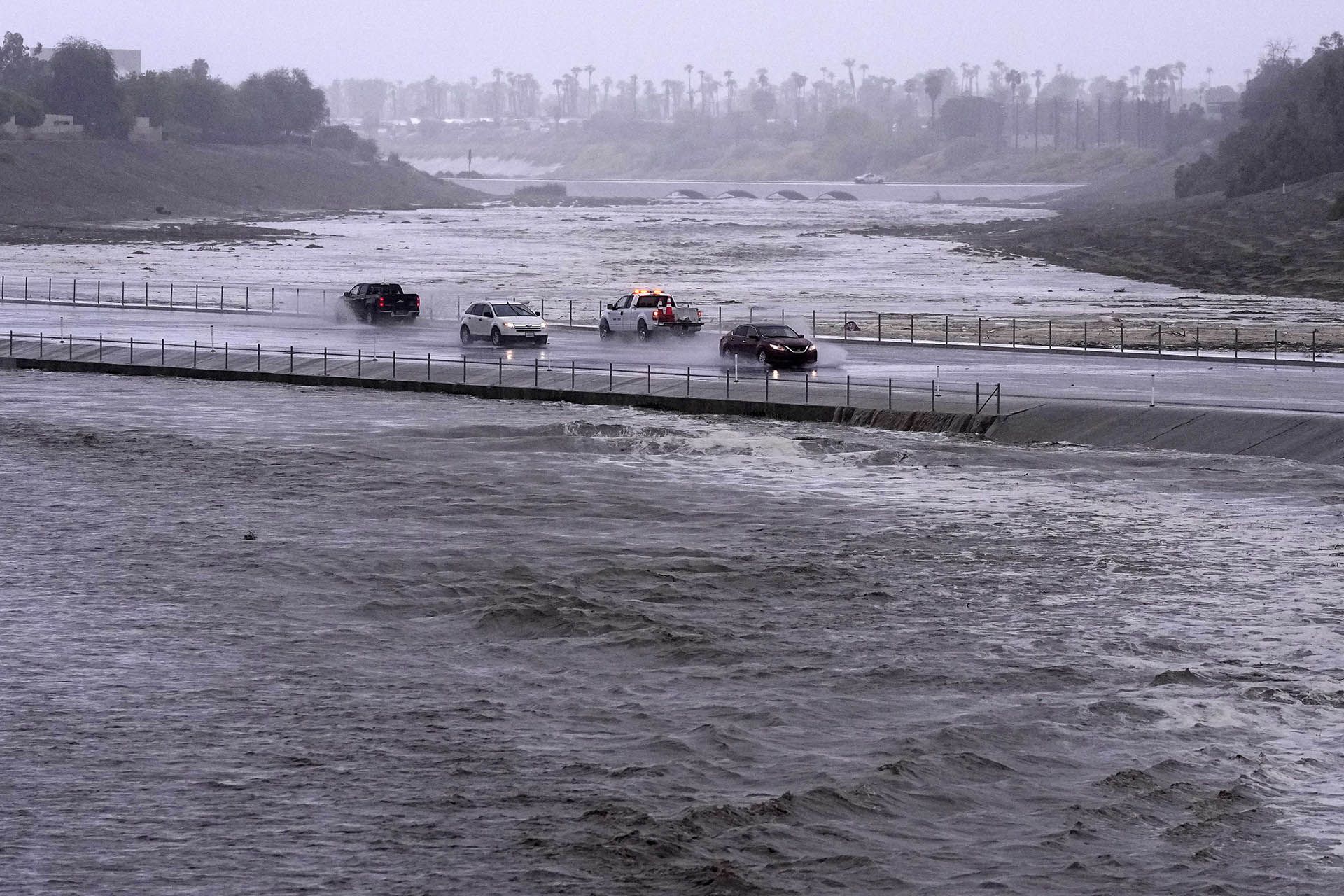 Los vehículos cruzan una cuenca de control de inundaciones que casi ha llegado a la calle, el domingo 20 de agosto de 2023, en Palm Desert, California. (Foto AP/Mark J. Terrill)