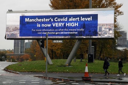 People walk past a sign about COVID-19, amid the outbreak of the coronavirus disease (COVID-19), in Manchester, Britain, October 23, 2020. REUTERS/Phil Noble