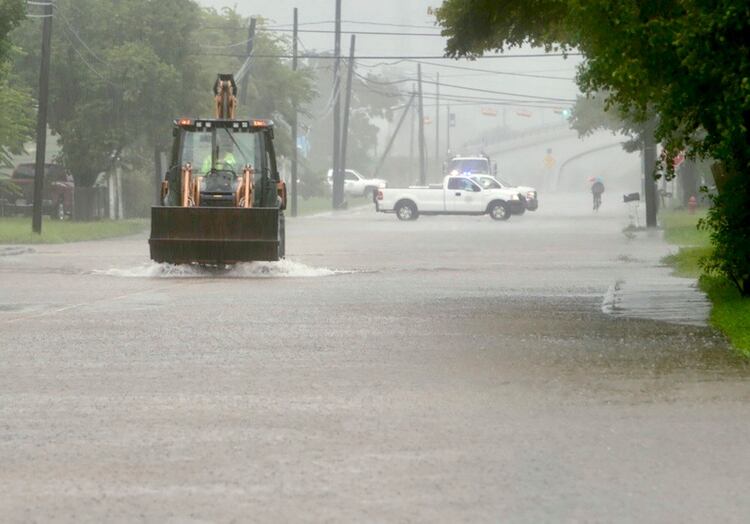 A backhoe drives down a flooded S. Velasco Blvd. in Freeport, Texas, Wednesday, Sept. 18, 2019. According to Freeport police, impacts on homes have been minimal so far with one of the main problems being people driving too fast through water and pushing the flooding into houses with their wake. ( Mark Mulligan /Houston Chronicle via AP)