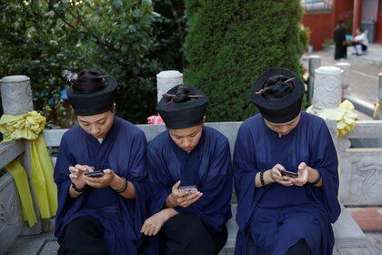 Monjes taoistas en el templo de Jiuyang, en Jinan, China, miran sus celulares REUTERS/Tingshu Wang 