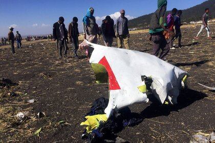 FOTO DE ARCHIVO: La gente pasa junto a una parte de los restos en la escena del accidente aéreo del vuelo ET 302 de Ethiopian Airlines, cerca de la ciudad de Bishoftu, al sureste de Addis Abeba, Etiopía, el 10 de marzo de 2019. (REUTERS / Tiksa Negeri / Foto de archivo)