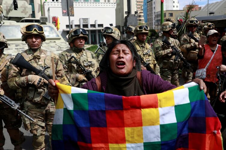 Una manifestante pro Morales muestra la bandera Wiphala frente a miembros de las fuerzas de seguridad en La Paz (REUTERS/Henry Romero)