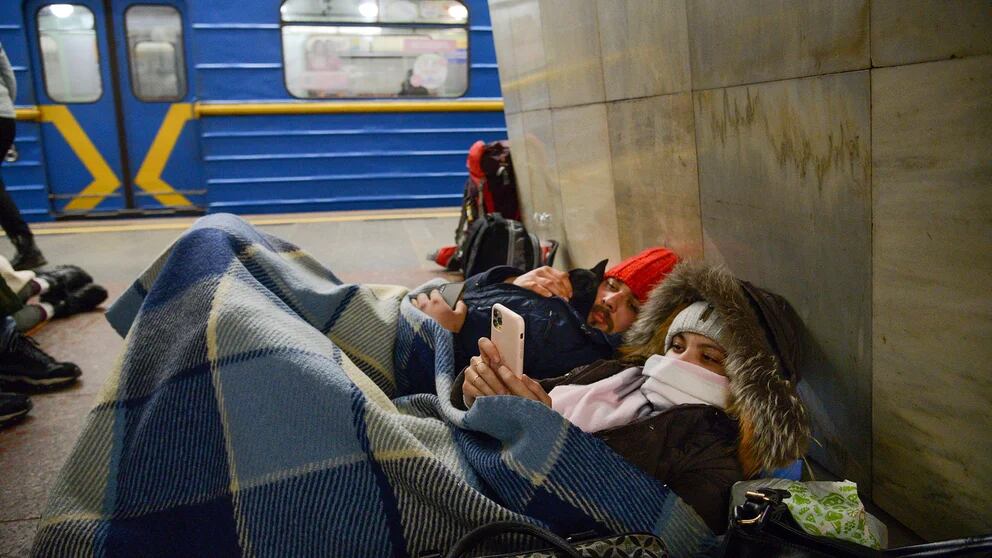 Dos personas reposan en el anden del metro de Kiev, usándolo como refugio antibombas, el jueves 24 de febrero de 2022, en Kiev, Ucrania. (AP Foto/Zoya Shu)
