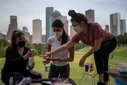 Tres mujeres se ponen desinfectante de manos en Houston, Texas. Foto: REUTERS/Adrees Latif