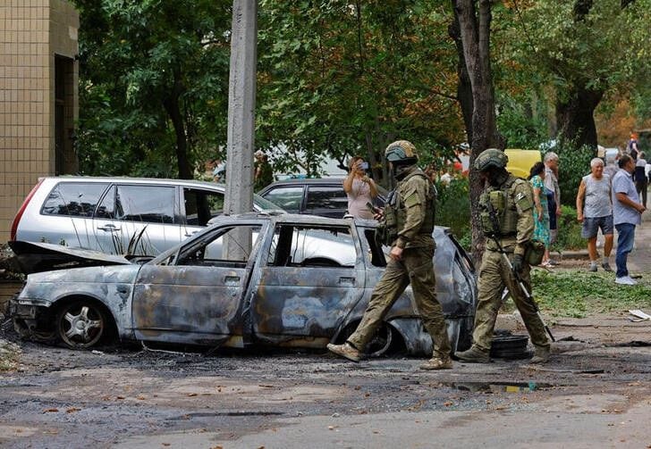 Soldados rusos pasan junto a un auto quemado tras un bombardeo en Donetsk, en territorio ucraniano controlado por Rusia (REUTERS/Alexander Ermochenko)