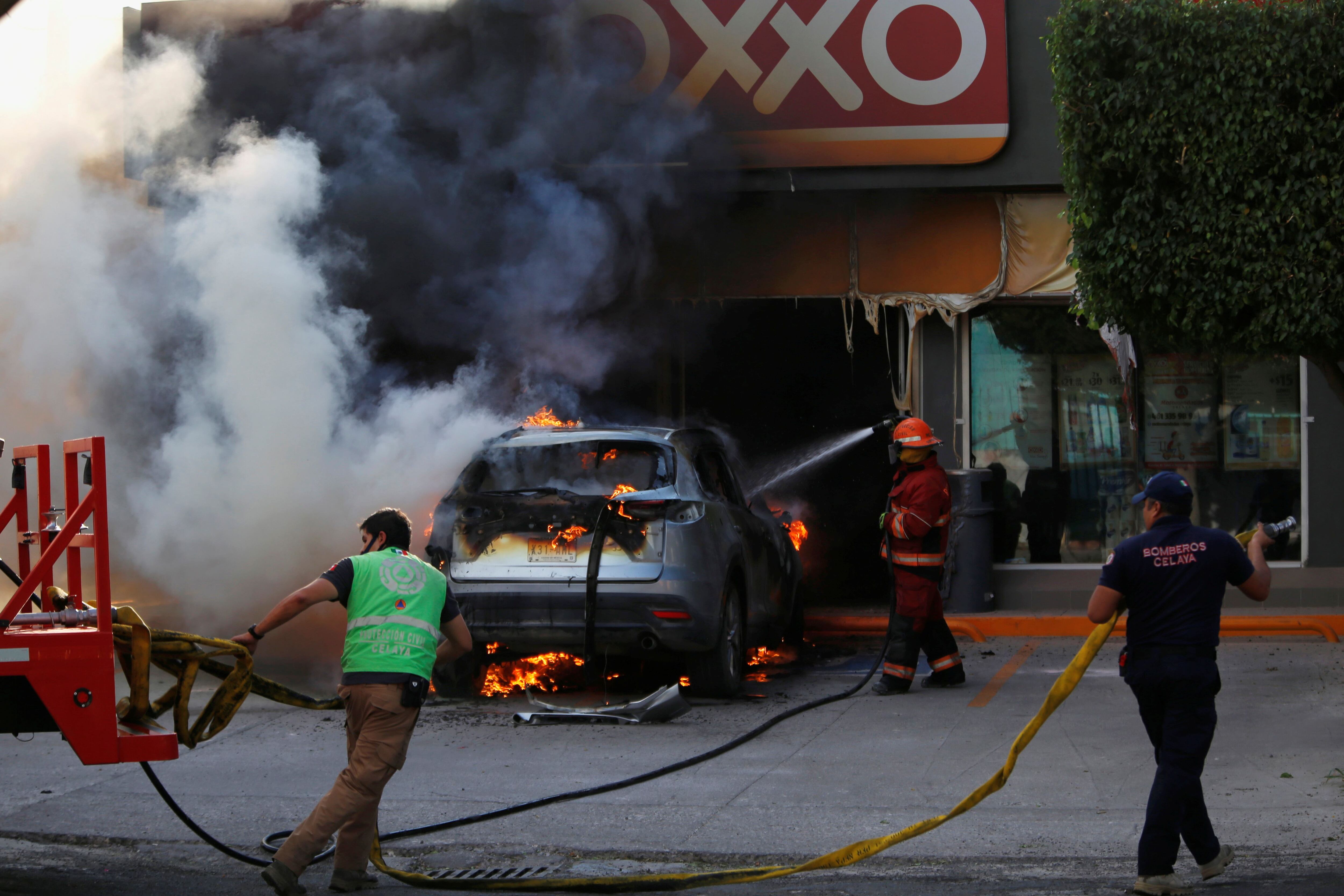 Firefighters work on a burning car outside a store after an operation by security forces against organized crime in Celaya, in Guanajuato state, Mexico June 20, 2020. REUTERS/Sergio Maldonado