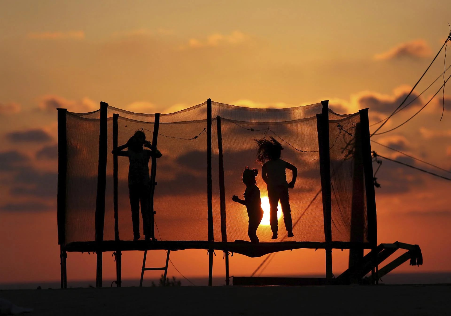 Varios niños palestinos juegan en una cama elástica mientras esperan el fin de la jornada de ayuno al atardecer en una playa del sur de Gaza, Palestina, durante el mes sagrado de Ramadán