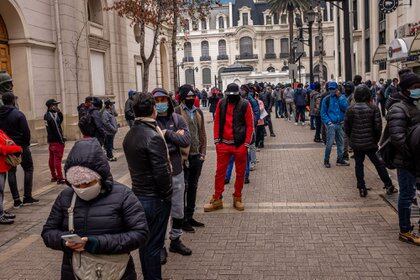 Usando mascarillas protectoras, personas hacen fila fuera de la oficina de una administradora de fondos de pensiones en Santiago, Chile
